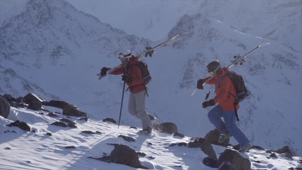 Two skiers hike up a mountain.