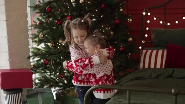 Little Girl Hugs Her Elder Sister in Christmas Eve