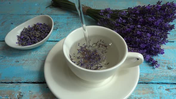 Tea from fresh lavender flowers on a vintage wooden background. Tea is brewed in hot water in a cup.