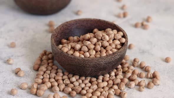 Pour Raw dry chickpea into a wooden bowl close up