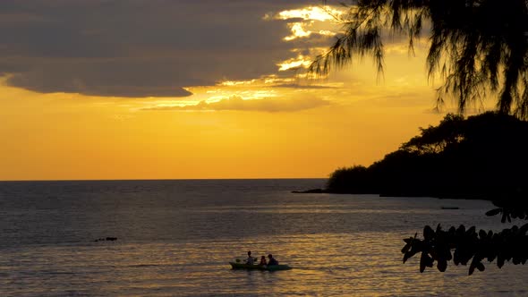 Silhouette of people in a kayak on the ocean at sunset