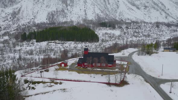 Slow aerial orbit around red Kåfjord wooden church, Olderdalen, Arctic