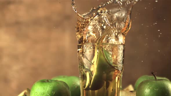 Super Slow Motion a Piece of Fresh Apple with Splashes Falls Into a Glass of Juice