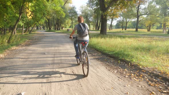 Teenage Boy Rides Bike in City Park at Sunny Day. Healthy Lifestyle Concept.