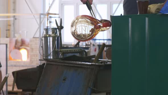 Glassblower Forms Vase of Hot Workpiece with Tongs in Shop