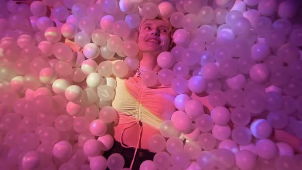 Young Woman Playing with Balls in a Dry Pool Spotlight with Abstract Video Art