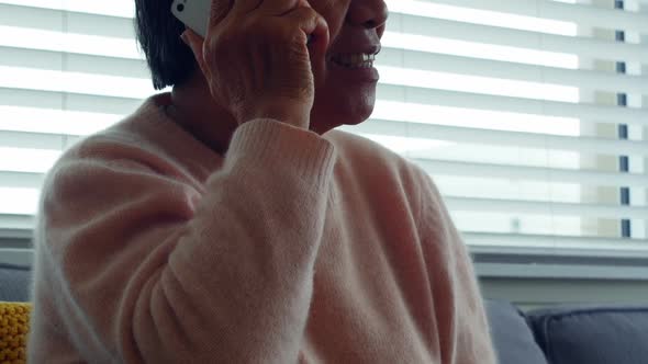 Senior woman talking on mobile phone in living room