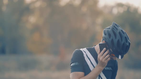 Cyclist In Sunglasses Talking On Mobile Phone. Cyclist On Sportswear, Sunglasses And Helmet Resting.