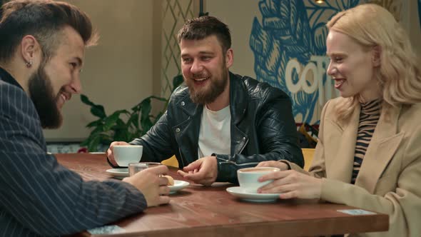 A white-skinned girl drinks filter coffee in a coffee shop in the company of cheerful friends.