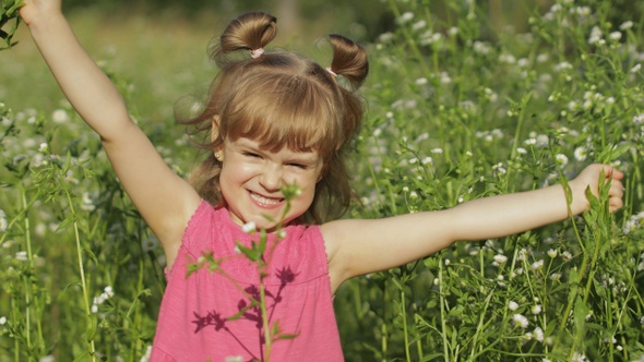 Little Blonde Child Girl in Pink Dress Stay on Flower Chamomile Grass Meadow. Bouquet of Daisies