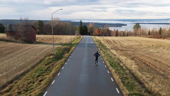 Man Skiing Down Swedish Countryside Road Near Ostersund, Sweden During Sunset. 4K Drone.