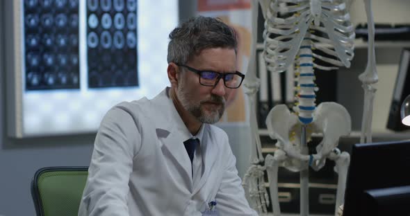 Male Doctor Analyzing Human Skeleton Model