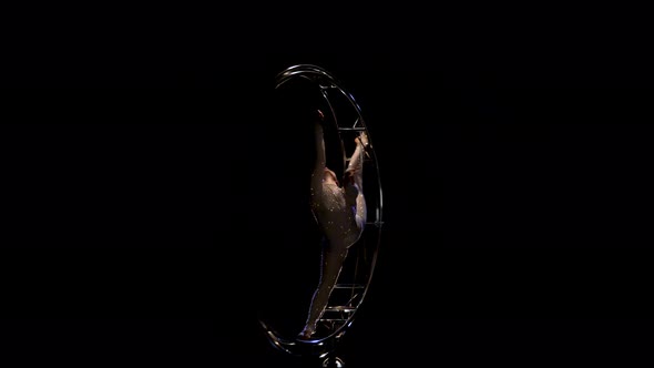 Gymnast Rotates on a Metal Structure Moon in a Vertical String. Black Background