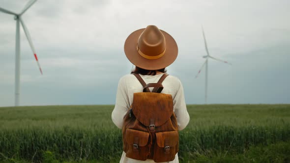 Attractive woman in the field against the background of windmills