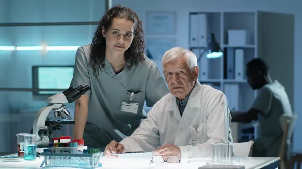 Portrait of Elderly Scientist with Young Female Assistant in Lab