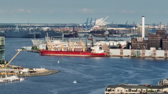 Cargo ships dock at port in USA. Long aerial zoom lens during golden hour light on hazy summer day.