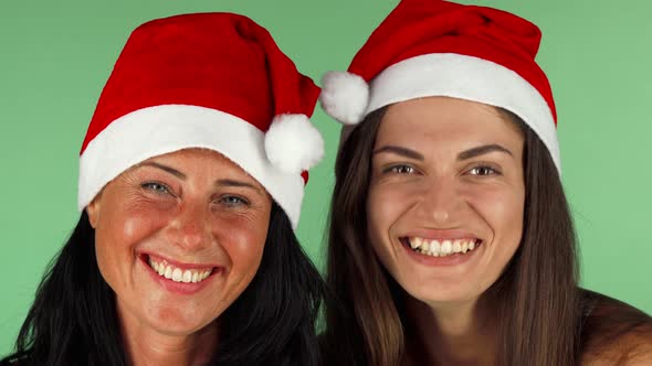Happy Women in Santa Claus Hats Laughing Joyfully To the Camera