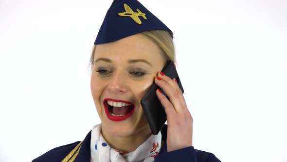 A Young Beautiful Stewardess Talks on a Smartphone with a Smile - Face Closeup - White Screen Studio