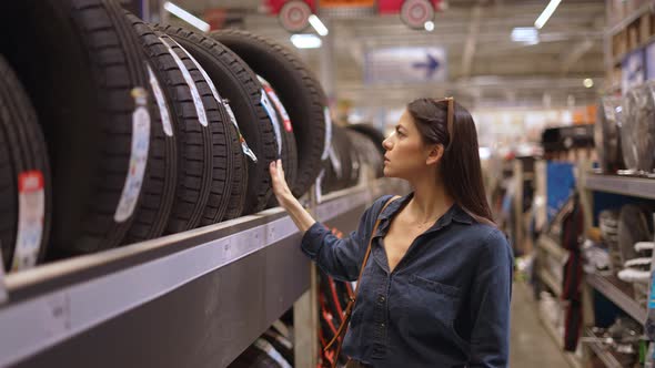 Young Woman Customer Buying New Tires in Department with Car Goods