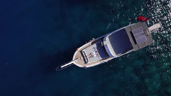 Top Drone View of Man and Woman Lying on the Deck of Yacht in the Blue Sea at Summer Day