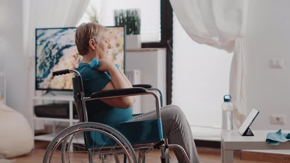 Aged Person Sitting in Wheelchair Using Dumbbells to Exercise