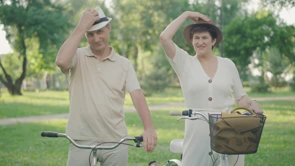 Portrait of Joyful Man and Woman Taking Off Hats and Smiling at Camera. Positive Caucasian Couple