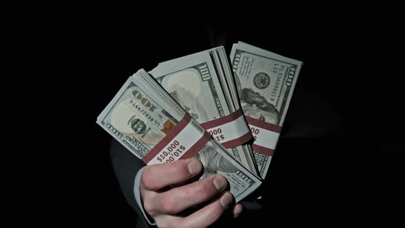 Three Stacks of 10000 American Dollars Bundles in Male Hands on Black Background