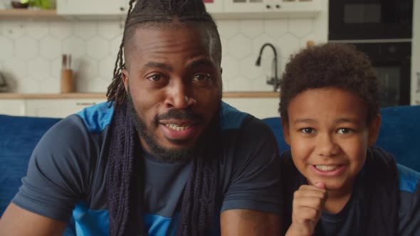 Excited African Father and Son Watching Sport Game on Tv and Celebrating Victory