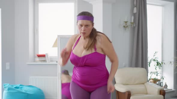 Medium Shot Portrait of Funny Overweight Caucasian Woman Running in Place Looking at Camera