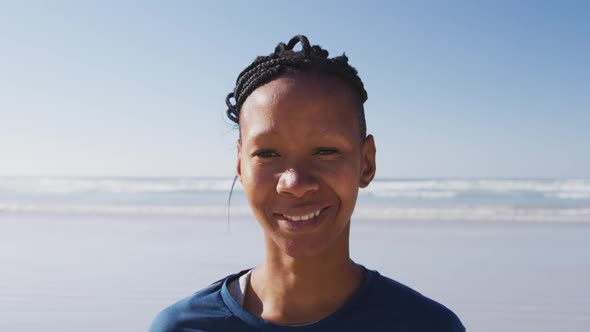 African American woman looking at camera and smiling on the beach and blue sky background