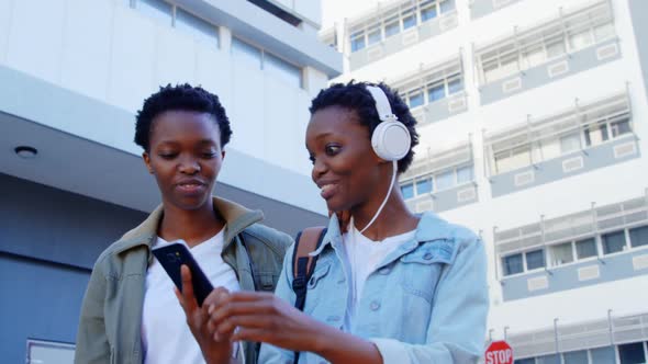 Twin sisters listening music on headphones in the city 4k