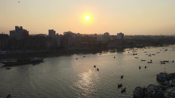 Buriganga river port beside urban city in sunrise with boats - aerial establishing drone flight shot