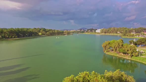 Flycam Removes From Tranquil Green Lake with Island