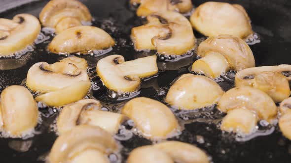 Golden Slices of Champignons are Fried Into a Hot Pan with Oilin Close Up