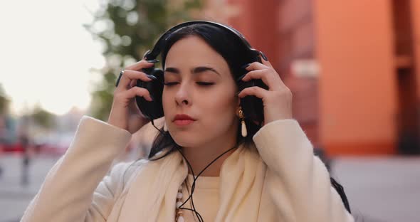 Stylish Woman Puts on Headphones in the City