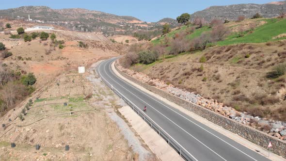 Cyclist is cycling down from mountain pass, aerial drone view