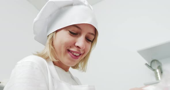Young Female Chef In White Apron And Hat Smiling At Camera
