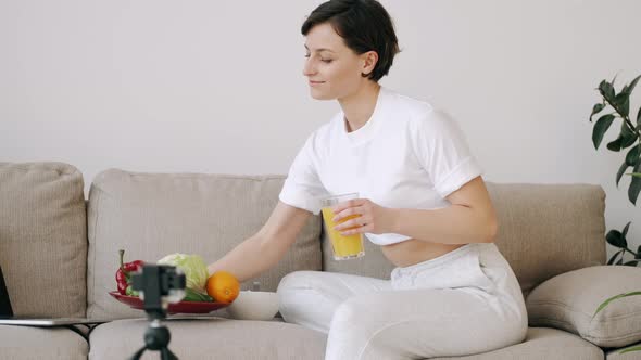 A Pretty Fit Woman with Fresh Juice Is Making a Video