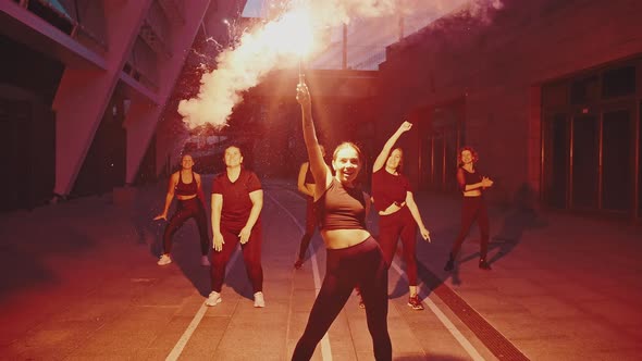 Group of Girls Dancing in the Street with a Torch or Smoke Bomb