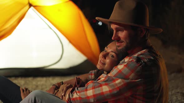 Man Hugging Woman in Front of the Bonfire on Beach Party in the Dark