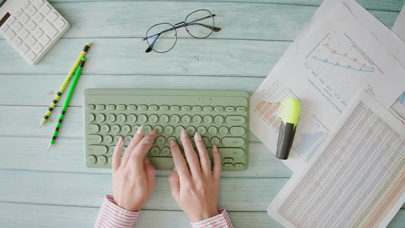 A Worker is Typing on Computer Keyboard and Analyzing Business Documents