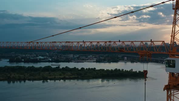 Aerial Horizontal Flight Along Construction Crane at Colorful Sunset