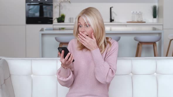 Shocked Senior Woman Received Bad News on Smartphone While Sitting on Sofa at Home