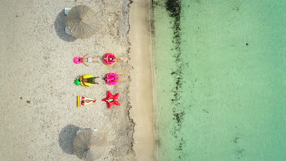 Aerial view of people lying on big inflatable mattresses on beach.