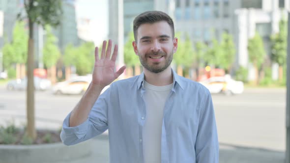 Welcoming Young Man Waving Hand for Hello Outdoor