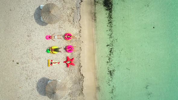 Aerial view of people lying on big inflatable mattresses on beach.