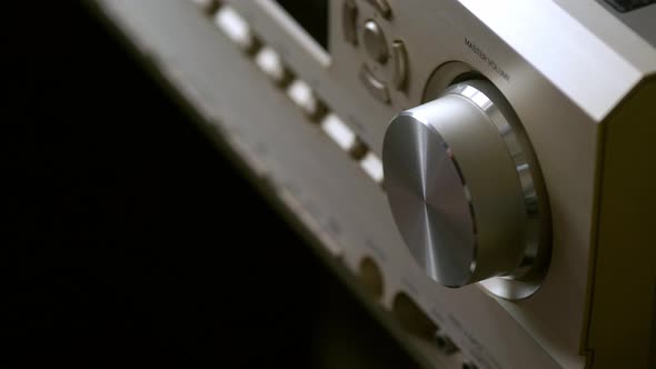 The hand is using the dust brush of the amplifier in the home theater system with buttons for broadc