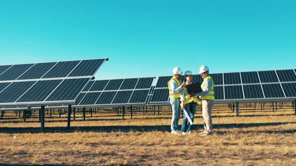 Solar Power Plant Workers, Solar Energy Industry Concept. Engineers Standing in Front of Solar