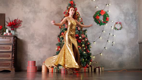 Beautiful Woman in Golden Evening Dress Spins and Dances Near Christmas Tree