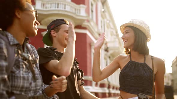 Travelers Giving Highfive Smiling Looking at Map Outside with Sun Behind Them Slow Motion